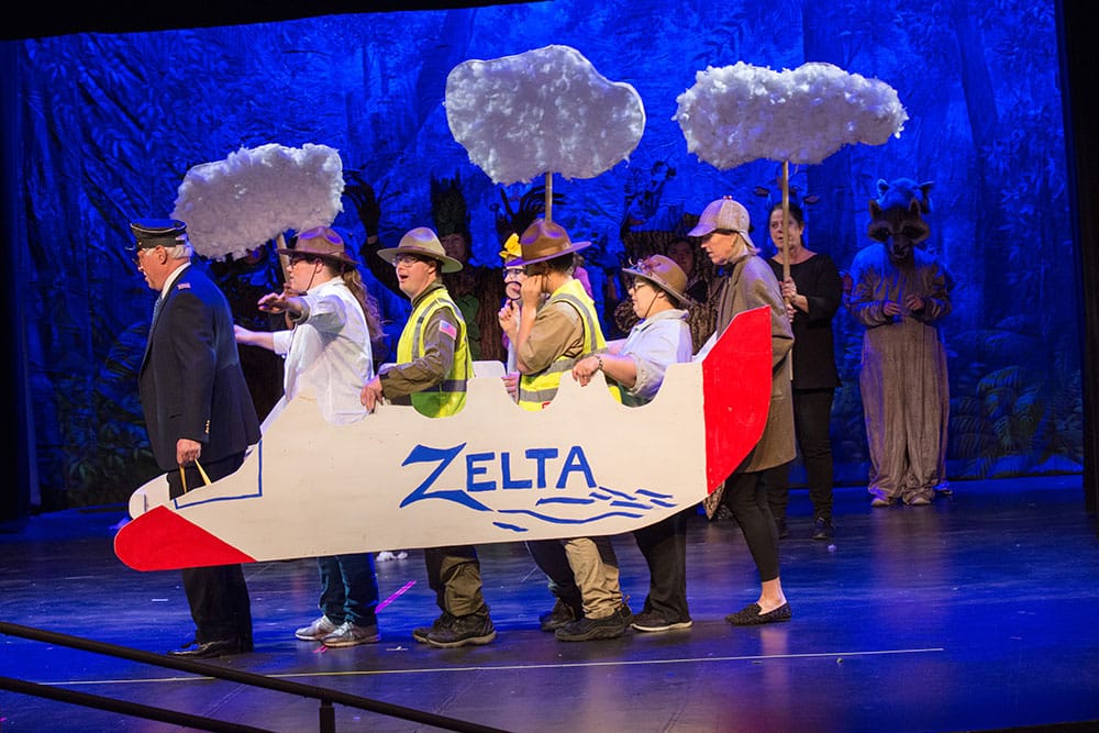 An ensemble performs onstage with a handmade airplane prop.