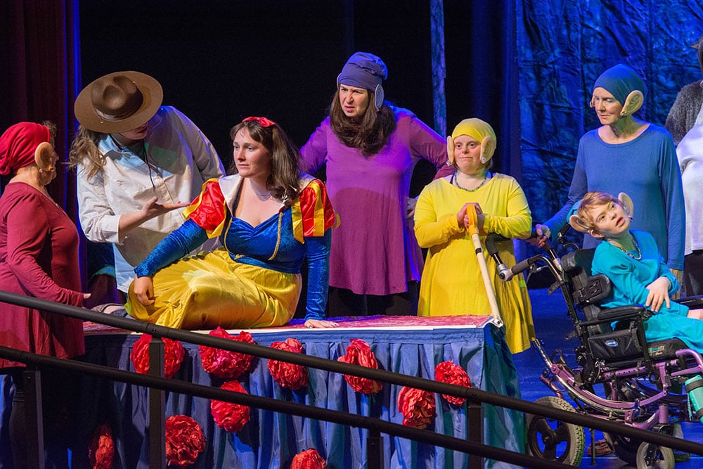 Performers in colorful costumes share a scene onstage.